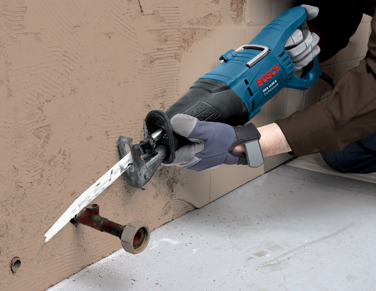 Eine Person mit Sicherheitsausrüstung schneidet mit einer Säbelsäge ein Metallrohr durch. Anwendungsbild