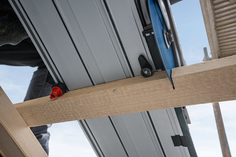 Eine Tauchsäge schneidet auf einer Baustelle durch einen Holzbalken. Anwendungsbild