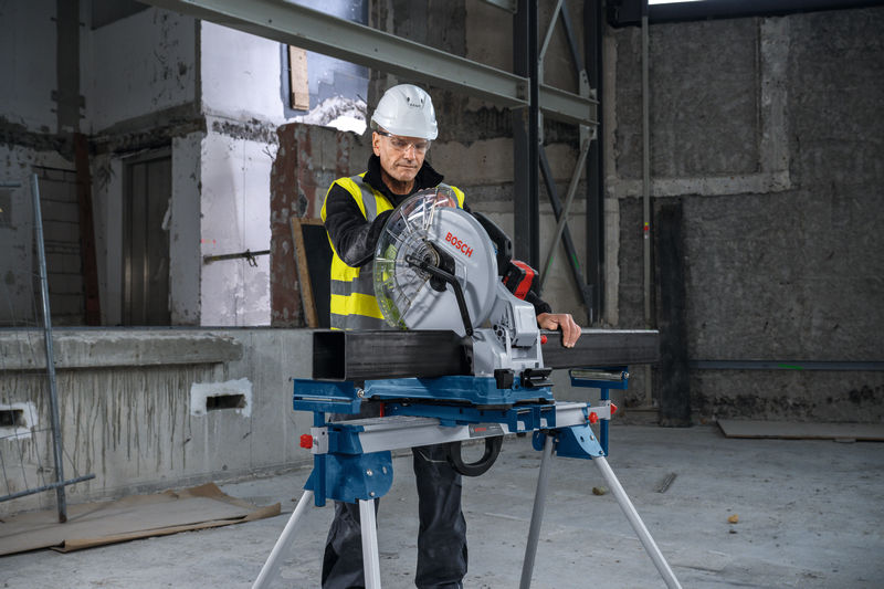 Eine Person mit Sicherheitsausrüstung bedient auf einer Baustelle eine Metalltrennsäge. Anwendungsbild