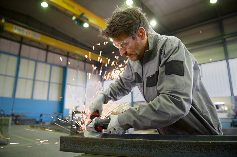 Eine Person mit Schutzausrüstung verwendet einen Winkelschleifer mit X-LOCK auf Metall. Anwendungsbild