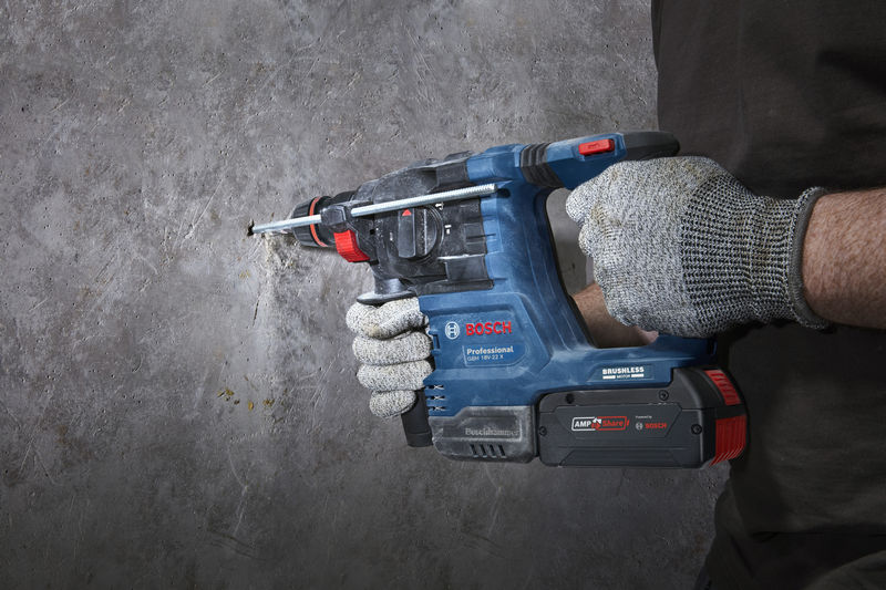 Eine Person mit Schutzausrüstung bohrt mit einem Bohrhammer in eine Betonwand. Anwendungsbild