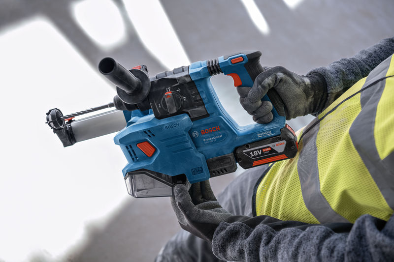 Eine Person mit Schutzausrüstung hält einen Akku-Bohrhammer. Anwendungsbild
