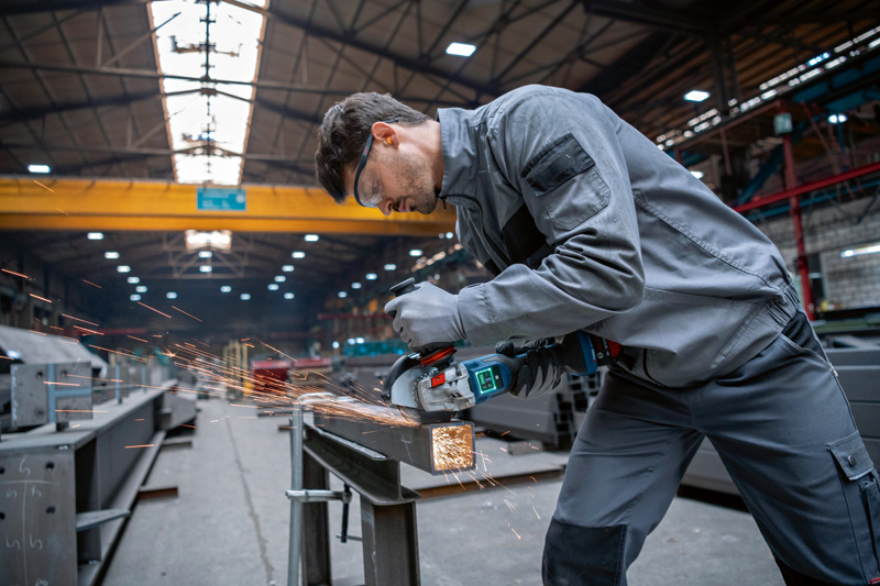 Ein Arbeiter mit Sicherheitsausrüstung schleift Metall in einer Industriewerkstatt. Anwendungsbild
