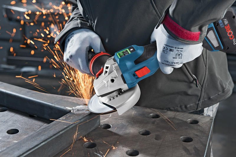 Eine Person mit Schutzausrüstung schleift mit einem Akku-Winkelschleifer einen Metallträger. Anwendungsbild