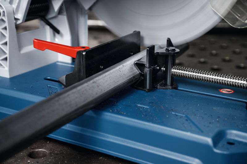 Metalltrennsäge schneidet ein quadratisches Metallrohr auf einer blauen Arbeitsfläche. Anwendungsbild