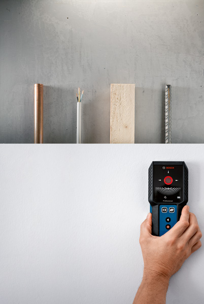 Eine Person sucht mit einem Detektor eine Wand nach Metall, Holz und elektrischen Leitungen ab. Anwendungsbild