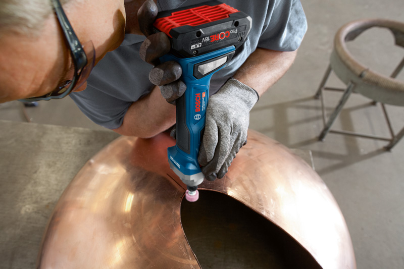 Eine Person mit Sicherheitsausrüstung schleift den Rand einer großen Metallkuppel. Anwendungsbild