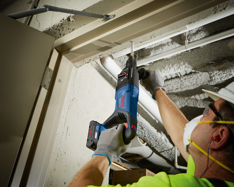 Person mit Schutzausrüstung bohrt mit Akku-Bohrhammer in eine Betondecke. Anwendungsbild