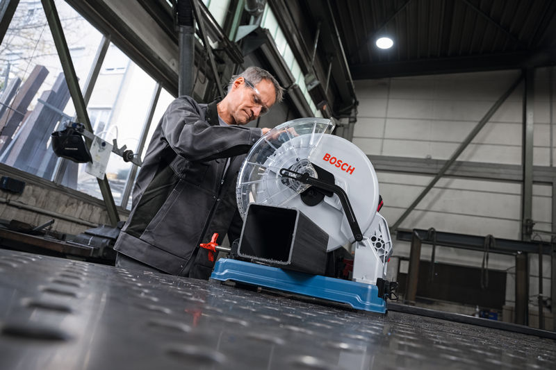 Eine Person mit Sicherheitsausrüstung bereitet eine Metalltrennsäge zum Durchtrennen eines Metallrohrs vor. Anwendungsbild