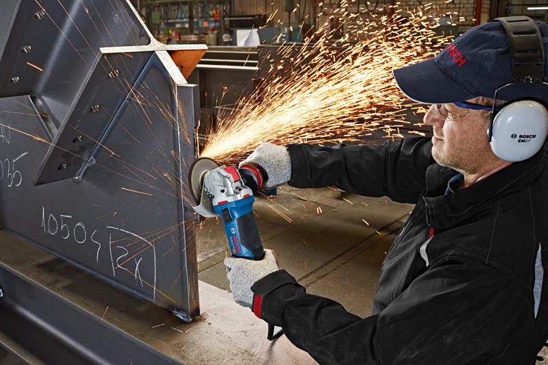 Eine Person mit Schutzausrüstung schleift Metall mit einem Winkelschleifer, wobei Funken entstehen. Anwendungsbild