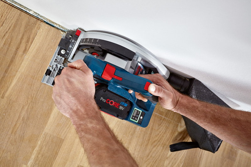 Eine Person bedient eine Akku-Kreissäge, um Holzböden in der Nähe einer Wand zu schneiden. Anwendungsbild