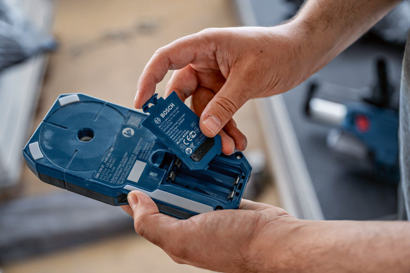 Eine Person setzt einen Akkupack in das blaue Gehäuse eines Elektrowerkzeugs ein. Anwendungsbild