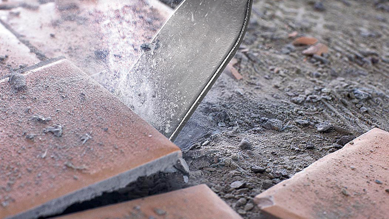 Meißel zerstört Keramikbodenfliesen und erzeugt Staub und Schutt. Anwendungsbild