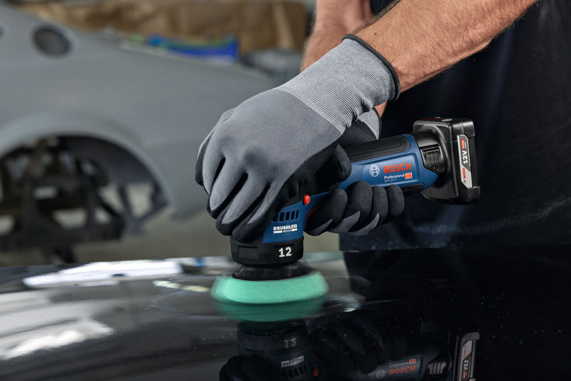 Eine Person mit Schutzausrüstung poliert eine Autooberfläche mit einer Akku-Poliermaschine. Anwendungsbild