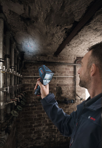 Eine Person scannt mit einem Thermodetektor eine feuchte Decke in einem Keller. Anwendungsbild