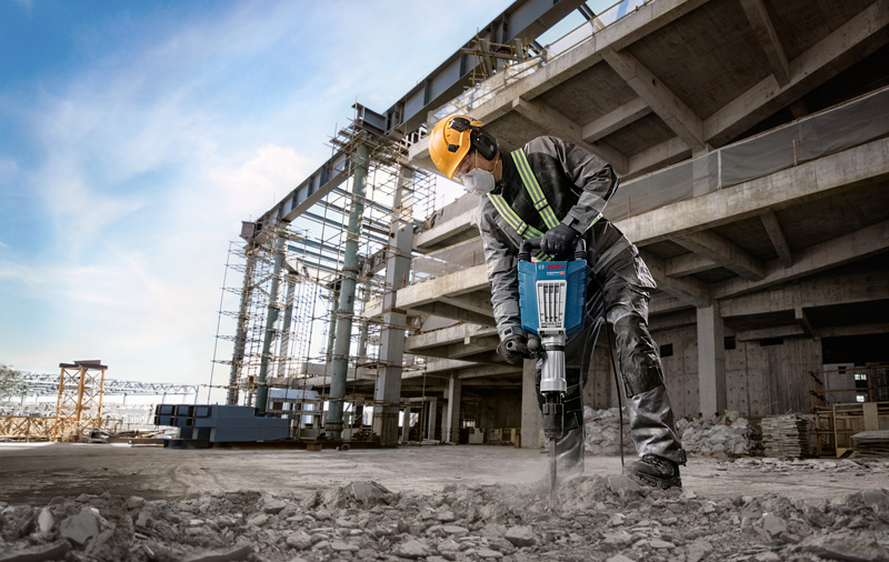Arbeiter benutzt Presslufthammer vor Ort. Key Visual