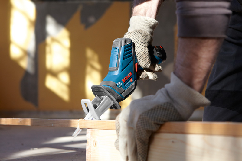 Eine Person mit Sicherheitsausrüstung verwendet eine kabellose Säbelsäge zum Schneiden von Holz. Anwendungsbild
