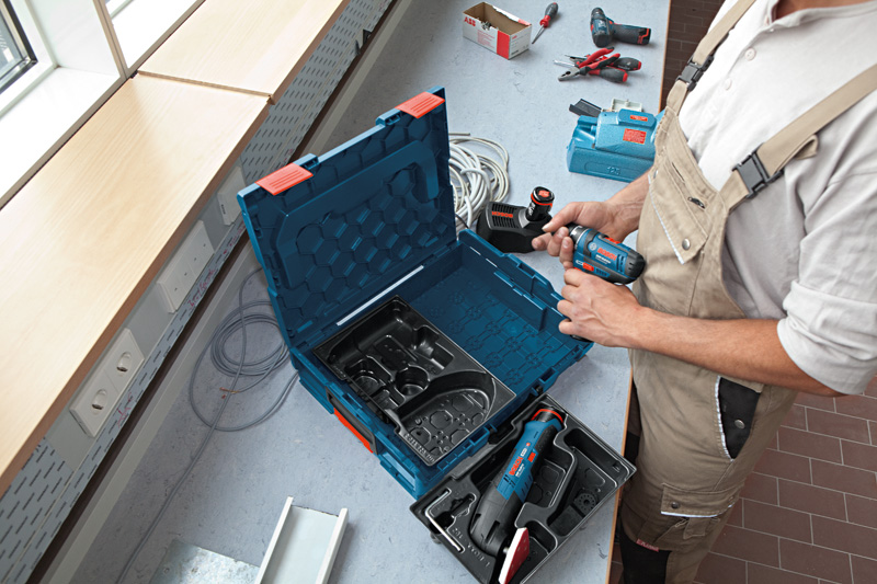 Eine Person mit Schutzausrüstung bereitet an einem Arbeitsplatz eine Akkubohrmaschine vor. Anwendungsbild