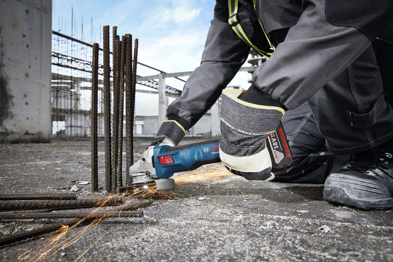 Eine Person mit Sicherheitsausrüstung schleift auf einer Baustelle Bewehrungsstahl, wodurch Funken entstehen. Anwendungsbild