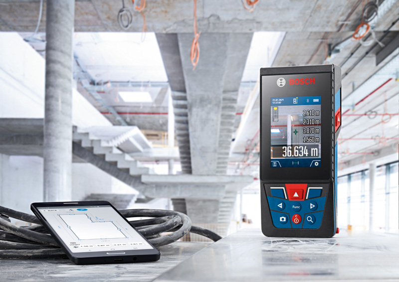 Lasermessgerät und digitales Tablet liegen auf einer Betonoberfläche in einem im Bau befindlichen Gebäude. Anwendungsbild