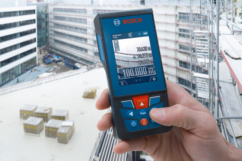 Eine Person verwendet ein Lasermessgerät auf einem Balkon auf einer Baustelle. Anwendungsbild