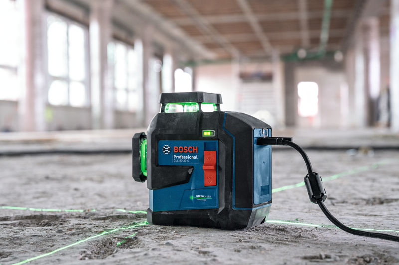 Lasernivellierwerkzeug, das hellgrüne Linien auf den Boden einer Baustelle projiziert. Anwendungsbild