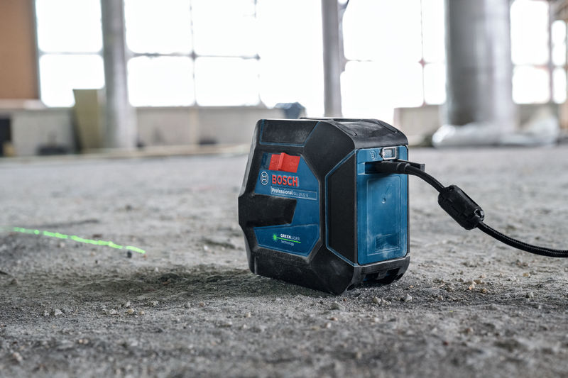 Lasernivelliergerät, das hellgrüne Linien auf den Boden einer Baustelle projiziert. Anwendungsbild
