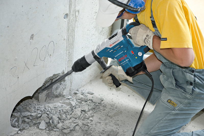 Eine Person mit Schutzausrüstung bohrt mit einem Bohrhammer in Beton. Anwendungsbild