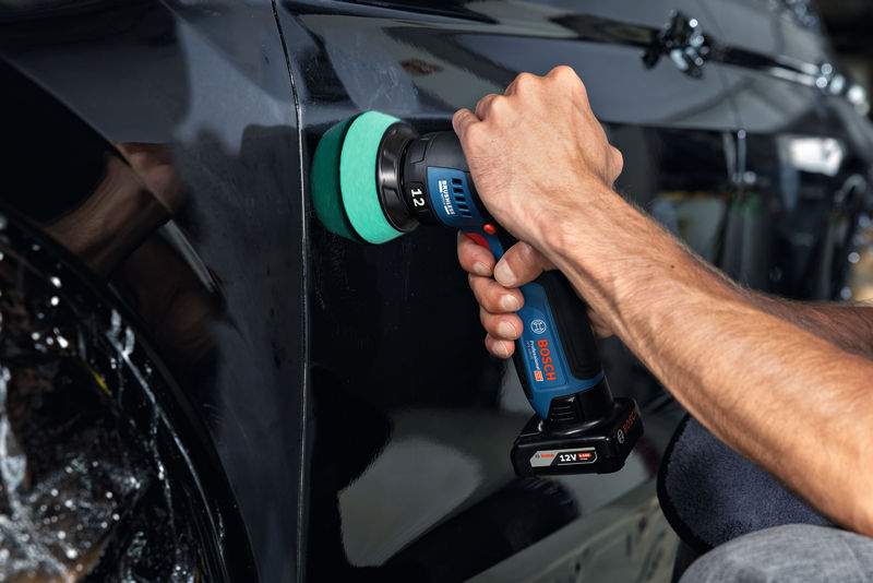 Eine Person poliert eine schwarze Autotür mit einer Akku-Poliermaschine. Anwendungsbild