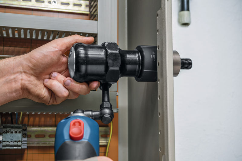 Eine Person bedient ein kabelloses hydraulisches Stanzwerkzeug an einer Metallplatte. Anwendungsbild