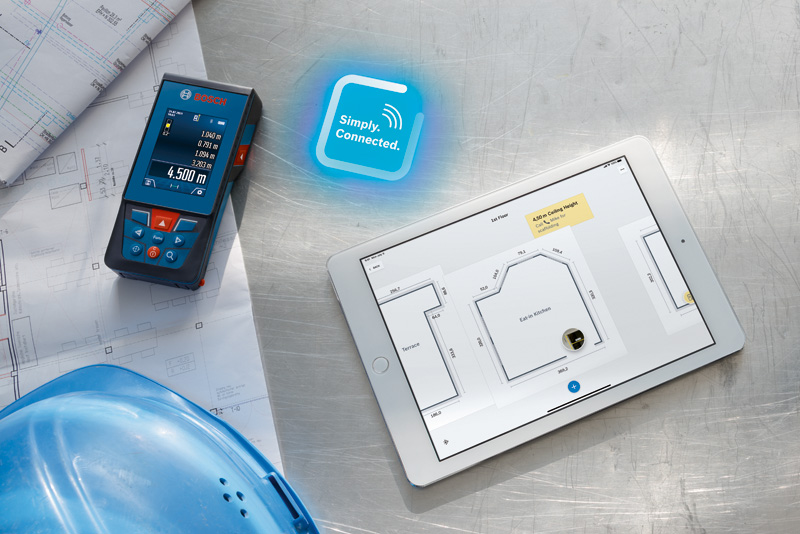 Lasermessgerät neben Bauplänen und Tablet mit digitalem Grundriss. Anwendungsbild