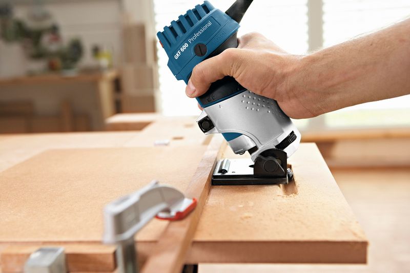 Eine Person verwendet eine Handfräse, um die Kante eines Holzbretts zu formen. Anwendungsbild