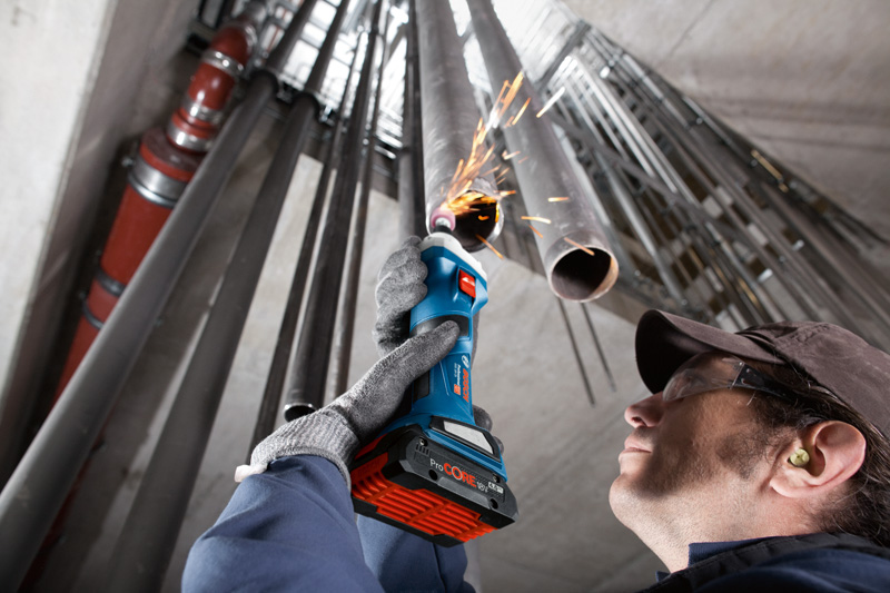 Eine Person mit Schutzausrüstung schleift mit einem Akku-Geradschleifer im Inneren eines Metallrohres. Anwendungsbild