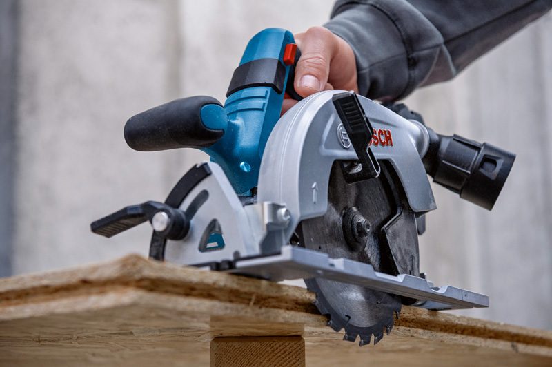 Eine Person schneidet auf einer Baustelle Holz mit einer Kreissäge. Anwendungsbild